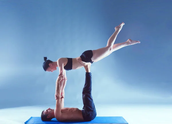 Ungt par öva acro yoga på matta i studio tillsammans. Acroyoga. Par yoga. Partner yoga. — Stockfoto