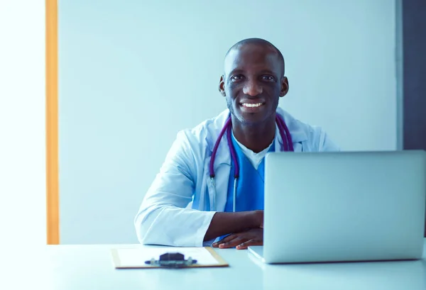 Portrait of young male doctor wearing headset while using computer at desk in clinic. Doctor.