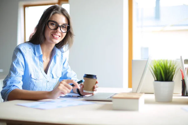 Giovane donna seduta al tavolo dell'ufficio, guardando lo schermo del computer portatile. Giovane donna — Foto Stock