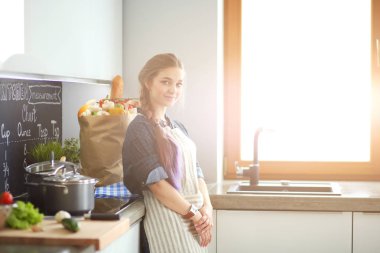 Mutfakta sobanın yanında duran genç bir kadın. .