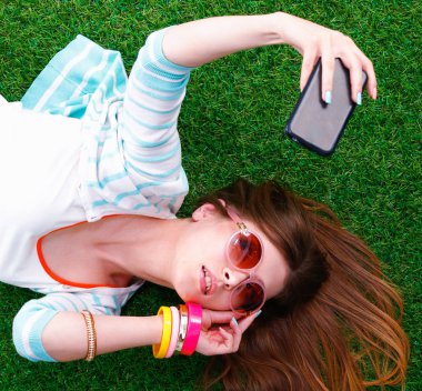 güzel ve genç birbayan yeşil çim yalan onu telefonla selfie yapma