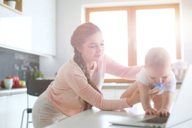 Annesi bebeğini evde parlak mutfakta ile.