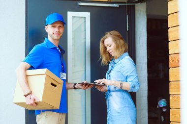 Mavi üniformalı gülümseyen kurye servis konseptine paket kutusu teslim eden teslimatçı. Mavi üniformalı gülümseyen teslimatçı.