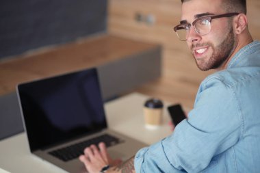 Genç bir telefonu kullanarak ve bir dizüstü bilgisayarda çalışan adam. Öğrenci manifatura telefon.