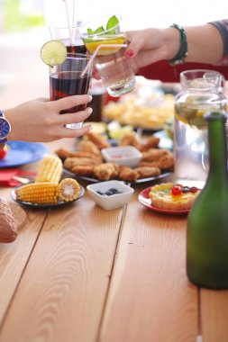 Ahşap masada otururken birlikte yemek yiyen bir grup insanın üst düzey görüntüsü. Masada yemek var. İnsanlar fast food yiyor..