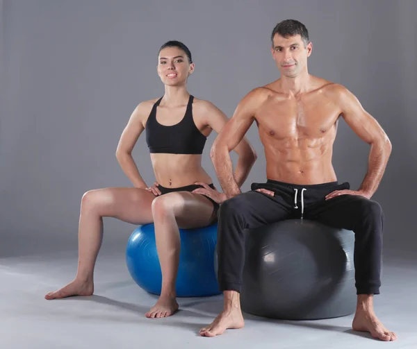 Twee lachende mensen met fitness bal in de sportschool. Persoonlijke fitness instructeur. Persoonlijke training. Training van de gymnastiek. — Stockfoto