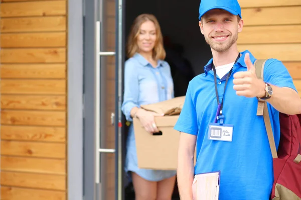 Mavi üniformalı gülümseyen kurye servis konseptine paket kutusu teslim eden teslimatçı. Mavi üniformalı gülümseyen teslimatçı.