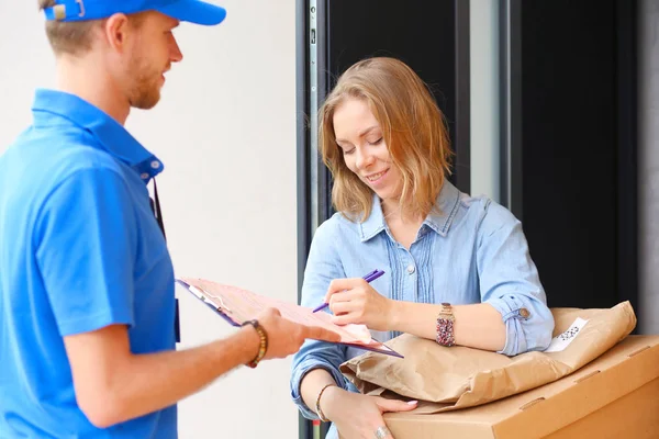Leende leverans man i blå uniform leverera paket låda till mottagaren - kurir service koncept. Leende leverans man i blå uniform — Stockfoto