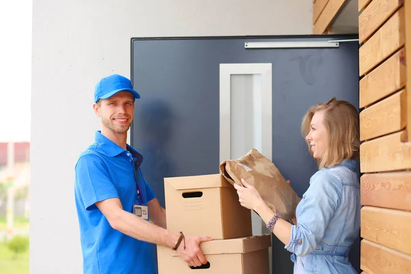 Leende leverans man i blå uniform leverera paket låda till mottagaren - kurir service koncept. Leende leverans man i blå uniform — Stockfoto