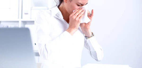 Junge Geschäftsfrau pustet sich die Nase, sitzt am Schreibtisch — Stockfoto