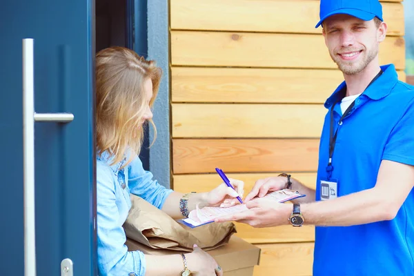 Mavi üniformalı gülümseyen kurye servis konseptine paket kutusu teslim eden teslimatçı. Mavi üniformalı gülümseyen teslimatçı.