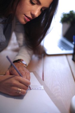 Masada oturan genç bir bayan. İş kadınıyım. Çizim. Öğrenci. İş yeri. Masa.