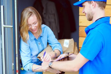 Mavi üniformalı gülümseyen kurye servis konseptine paket kutusu teslim eden teslimatçı. Mavi üniformalı gülümseyen teslimatçı.