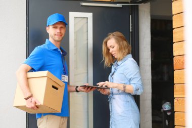 Mavi üniformalı gülümseyen kurye servis konseptine paket kutusu teslim eden teslimatçı. Mavi üniformalı gülümseyen teslimatçı.