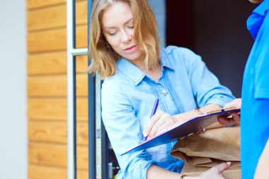 Mavi üniformalı gülümseyen kurye servis konseptine paket kutusu teslim eden teslimatçı. Mavi üniformalı gülümseyen teslimatçı.