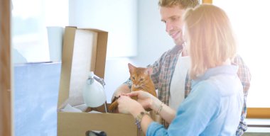 Genç bir çift yeni evinde büyük bir karton kutu taşıyor. Taşınıyorlar.