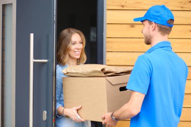 Mavi üniformalı gülümseyen kurye servis konseptine paket kutusu teslim eden teslimatçı. Mavi üniformalı gülümseyen teslimatçı.