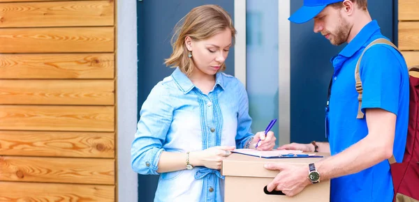 Mavi üniformalı gülümseyen kurye servis konseptine paket kutusu teslim eden teslimatçı. — Stok fotoğraf