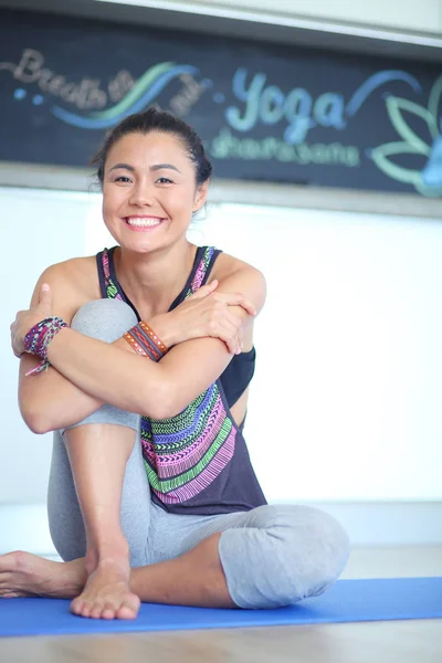 Retrato de una mujer sonriente de yoga sentada en la esterilla de yoga después del entrenamiento en el estudio de yoga. Yoga. Mujer. . — Foto de Stock