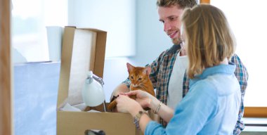 Genç bir çift yeni evinde büyük bir karton kutu taşıyor. Taşınıyorlar.