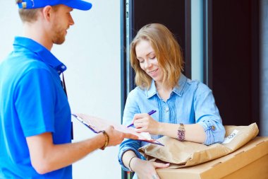 Mavi üniformalı gülümseyen kurye servis konseptine paket kutusu teslim eden teslimatçı. Mavi üniformalı gülümseyen teslimatçı.