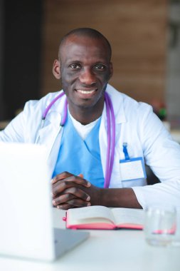 Masada dizüstü bilgisayarla çalışan genç bir Afrikalı doktor. Doktor bey. İşyeri