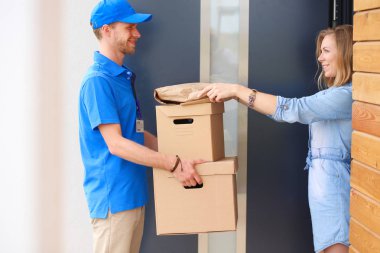 Mavi üniformalı gülümseyen kurye servis konseptine paket kutusu teslim eden teslimatçı. Mavi üniformalı gülümseyen teslimatçı.