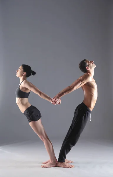 Young couple practicing acro yoga on mat in studio together. Acroyoga. Couple yoga. Partner yoga.