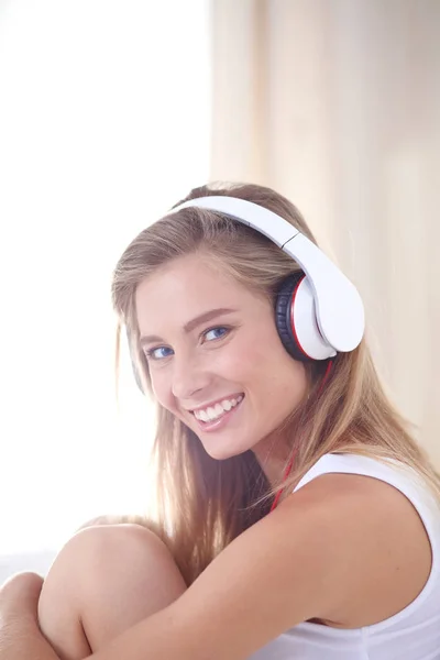 Retrato de una hermosa mujer en la mañana escuchando música sentada en la cama en casa. Retrato de mujer hermosa — Foto de Stock