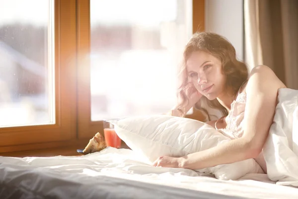 Pencere yakınındaki erken sabah yatakta yatan kadın. — Stok fotoğraf