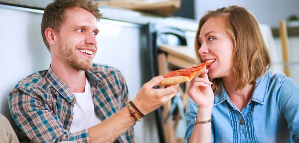 Pasangan muda memiliki istirahat makan siang pizza di lantai setelah pindah ke rumah baru dengan kotak di sekitar mereka — Stok Foto