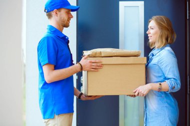 Mavi üniformalı gülümseyen kurye servis konseptine paket kutusu teslim eden teslimatçı. Mavi üniformalı gülümseyen teslimatçı.