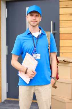 Mavi üniformalı gülümseyen kurye servis konseptine paket kutusu teslim eden teslimatçı. Mavi üniformalı gülümseyen teslimatçı.