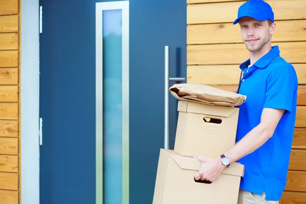 Leende leverans man i blå uniform leverera paket låda till mottagaren - kurir service koncept. Leende leverans man i blå uniform — Stockfoto