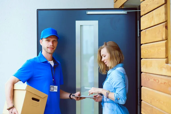 Mavi üniformalı gülümseyen kurye servis konseptine paket kutusu teslim eden teslimatçı. Mavi üniformalı gülümseyen teslimatçı.