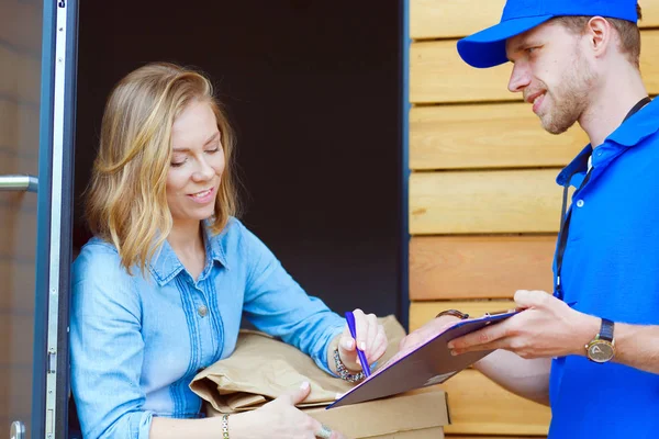 Mavi üniformalı gülümseyen kurye servis konseptine paket kutusu teslim eden teslimatçı. Mavi üniformalı gülümseyen teslimatçı.
