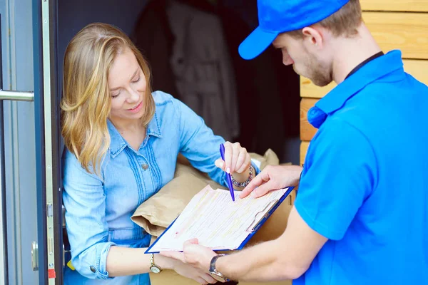 Mavi üniformalı gülümseyen kurye servis konseptine paket kutusu teslim eden teslimatçı. Mavi üniformalı gülümseyen teslimatçı.