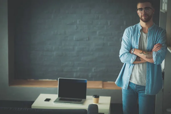 Young man holding laptop standing near wall. — Stock Photo, Image