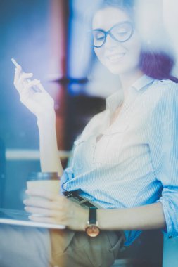 Ofis masasında dizüstü bilgisayarıyla oturan genç bir kadın. Pencereden bakıyor. Genç kadın.