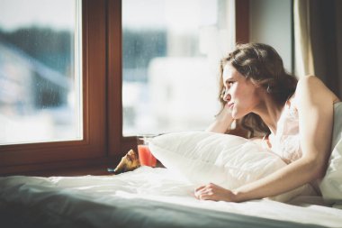 Pencere yakınındaki erken sabah yatakta yatan kadın.