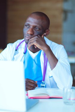 Masada dizüstü bilgisayarla çalışan genç bir Afrikalı doktor. Doktor bey. İşyeri