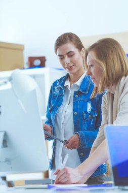 Masanın yanında duran iki genç kadın enstrüman, plan ve dizüstü bilgisayarla.