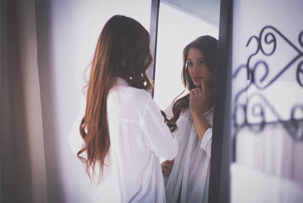 Giovane donna guardando se stessa riflesso nello specchio a casa. Giovane donna . — Foto Stock