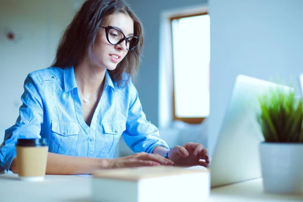 Ofis masasında oturan genç bir kadın dizüstü bilgisayar ekranına bakıyor. Genç kadın.