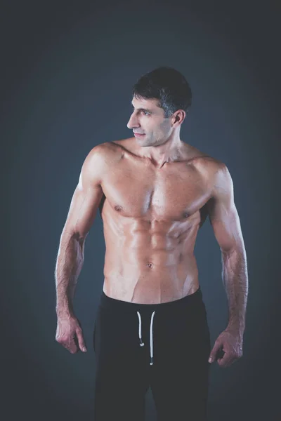 Homem musculado. Homem musculoso sobre um fundo cinzento mostrando músculos. Instrutor de fitness. Profissional de fitness. Treino. Aptidão dos homens . — Fotografia de Stock