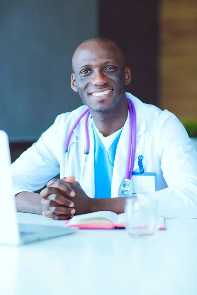 年轻的非洲医生在办公桌前的笔记本电脑上工作。医生。工作场所 — 图库照片