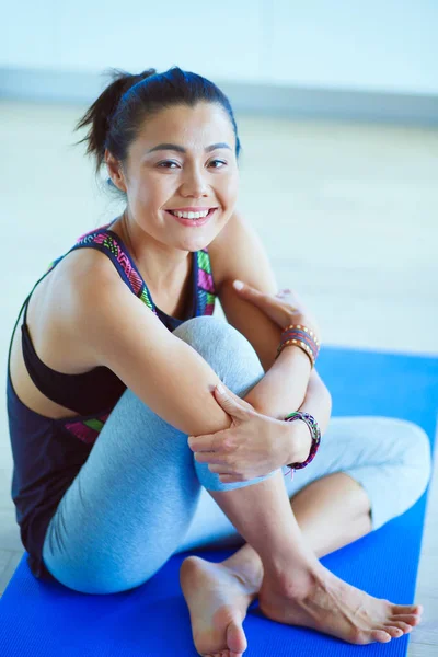 Retrato de una mujer sonriente de yoga sentada en la esterilla de yoga después del entrenamiento en el estudio de yoga. Yoga. Mujer. . — Foto de Stock