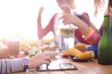 Ahşap masada otururken birlikte yemek yiyen bir grup insanın üst düzey görüntüsü. Masada yemek var. İnsanlar fast food yiyor..