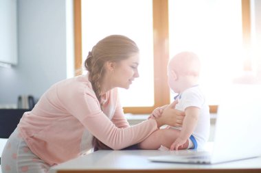 Annesi bebeğini evde parlak mutfakta ile.