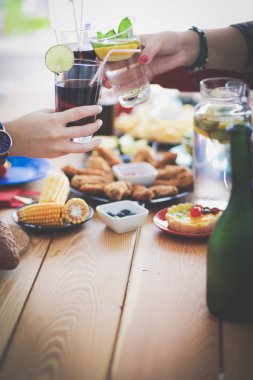 Ahşap masada otururken birlikte yemek yiyen bir grup insanın üst düzey görüntüsü. Masada yemek var. İnsanlar fast food yiyor..